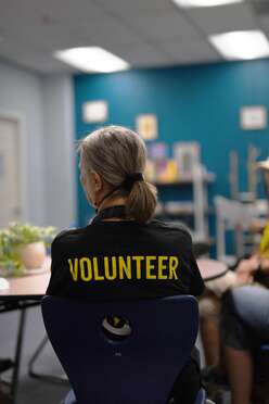 Phoenix Welcome Center Volunteer sits at a table collaborating with others during service
